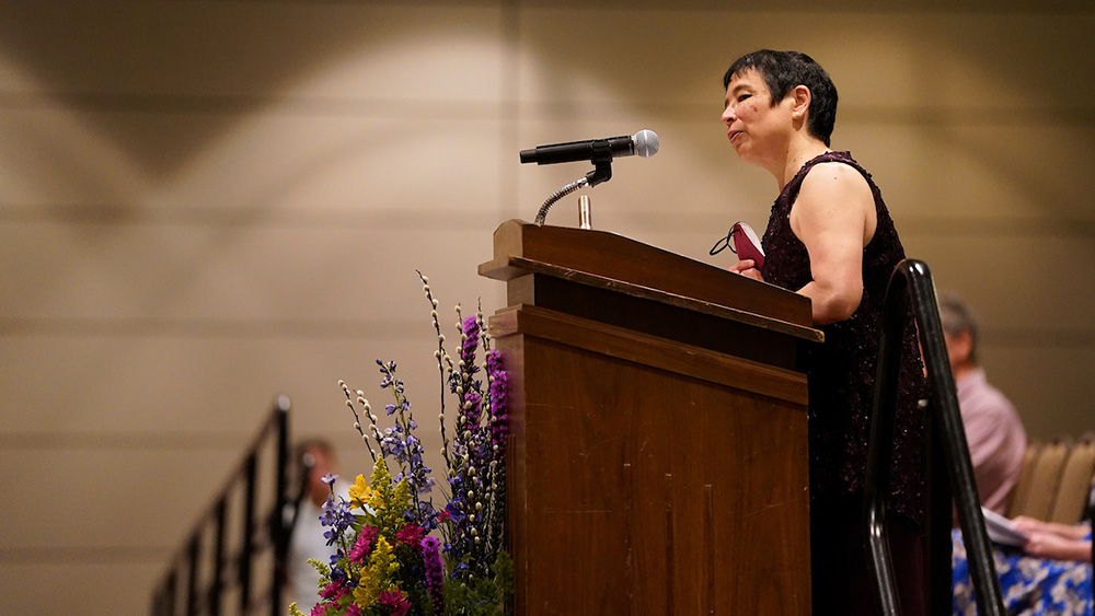 A woman speaks at the podium of an awards ceremony.