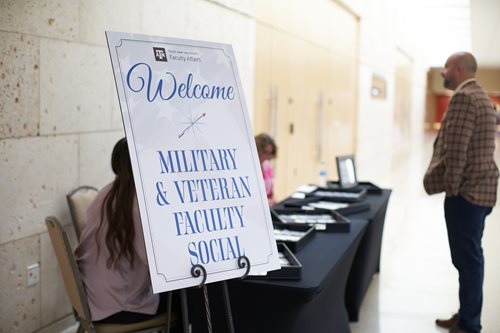 Check-in desk for military social with a sign reading "Welcome Military and Veteran Faculty Social"